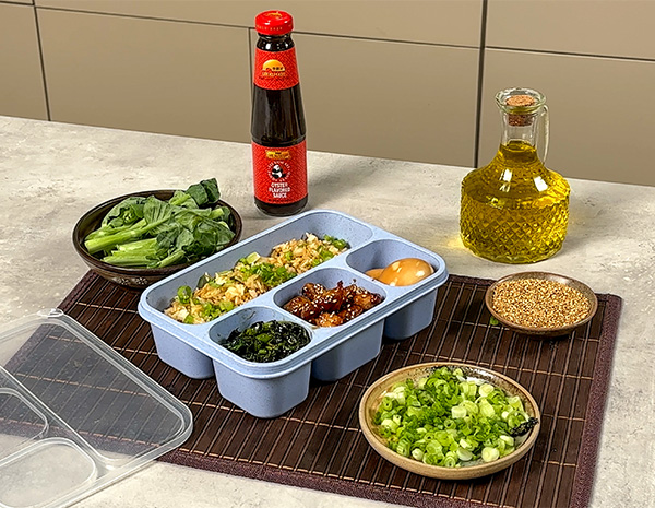 A bento lunch box recipe made with sesame chicken, quick fried rice, gai lan, and a soy marinated egg.