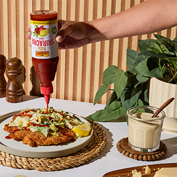 A caesar salad crispy chicken cutlet topped with Yuzu Sriracha.