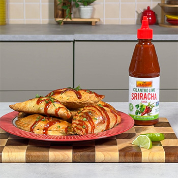 A recipe for Colombian empanadas filled with beef and potato and drizzled with cilantro lime sriracha.