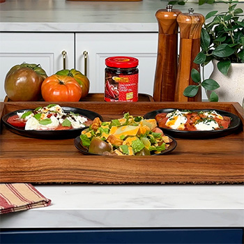 An heirloom tomato flight with a Caprese inspired tomato, a spicy Caesar tomato salad, and a whipped ricotta and hot honey tomato.