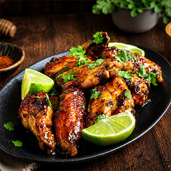 Une recette d'ailes de poulet au miel et à la Sriracha, avec un glaçage au miel piquant, à la fois sucré, salé et épicé.