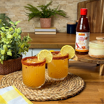A mocktail recipe for a hot honey lemonade with a chili crisp hot honey and chili lime salt rim.