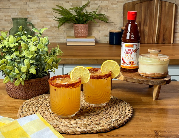 A mocktail recipe for a hot honey lemonade with a chili crisp hot honey and chili lime salt rim.
