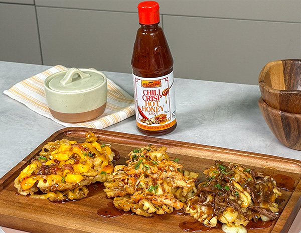 A platter of three loaded fries recipes topped with chili crisp hot honey.