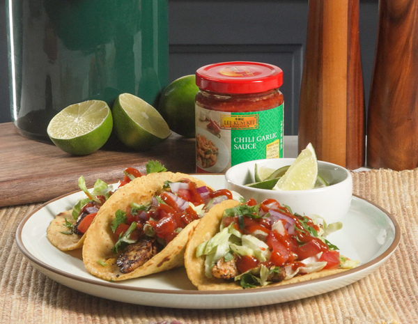 Plate with 3 jerk chicken tacos alongside some recipe ingredients