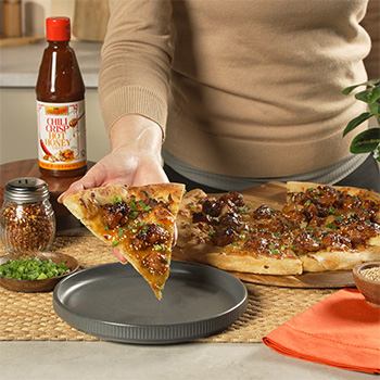 An orange chicken pizza recipe served with chili crisp hot honey.