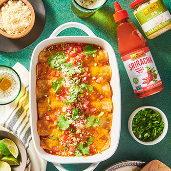 Prepared black bean enchilada recipe in a casserole dish, alongside toppings and the Lee Kum Kee sauces used in the dish.