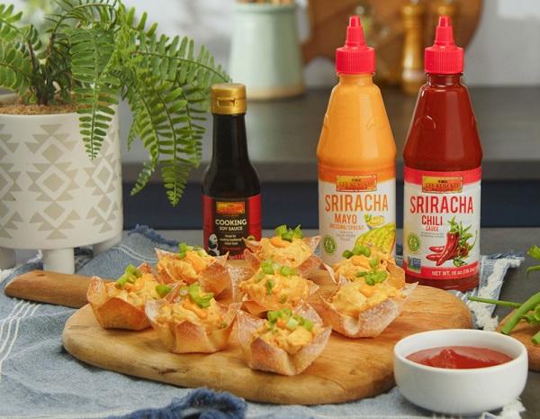 Crab rangoon cups on a serving board, alongside the LKK sauces used in the dish