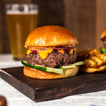 A recipe for Two Hoisin Sauce Burgers on a dark wood cutting board with crosscut fries 