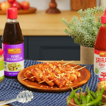 A plate of prepared rice cake skewers surrounded by ingredients and Lee Kum Kee sauces