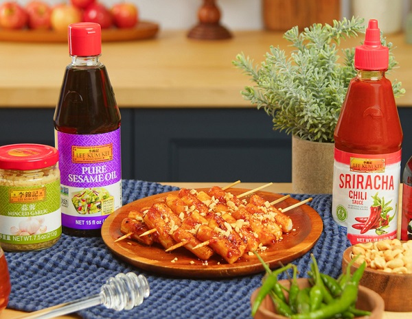 A plate of prepared rice cake skewers surrounded by ingredients and Lee Kum Kee sauces