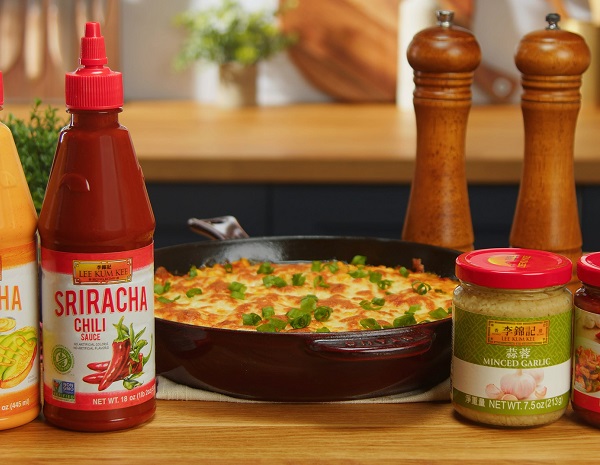 A heavy cast iron skillet containing prepared Korean-style cheese corn, surrounded by Lee Kum Kee ingredients