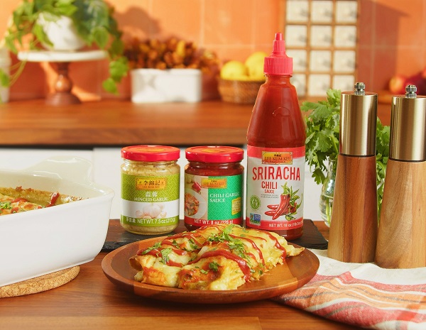 Leftover turkey enchiladas on a plate next to the casserole dish they were prepared in, alongside the Lee Kum Kee sauces used in the dish