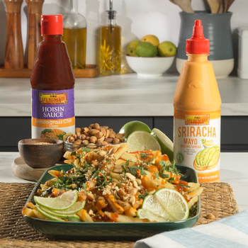 Prepared loaded Vietnamese street fries from Lee Kum Kee’s loaded fries recipe, served with bottles of Lee Kum Kee Lemongrass Chili Flavored Hoisin Sauce and Lee Kum Kee Sriracha Mayo.