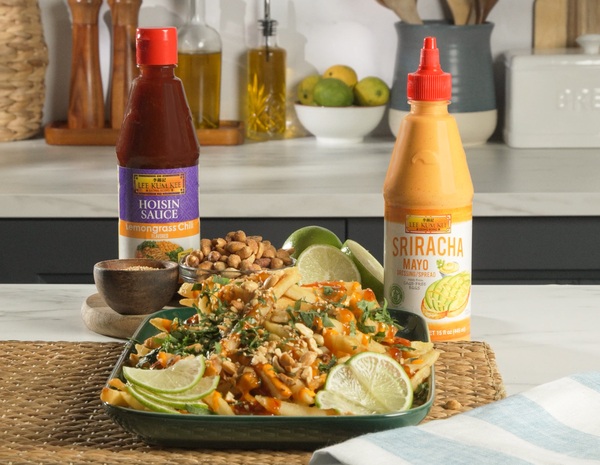 Prepared loaded Vietnamese street fries from Lee Kum Kee’s loaded fries recipe, served with bottles of Lee Kum Kee Lemongrass Chili Flavored Hoisin Sauce and Lee Kum Kee Sriracha Mayo.
