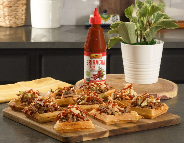 Pulled pork waffle bites on a serving platter, alongside Lee Kum Kee sriracha sauce