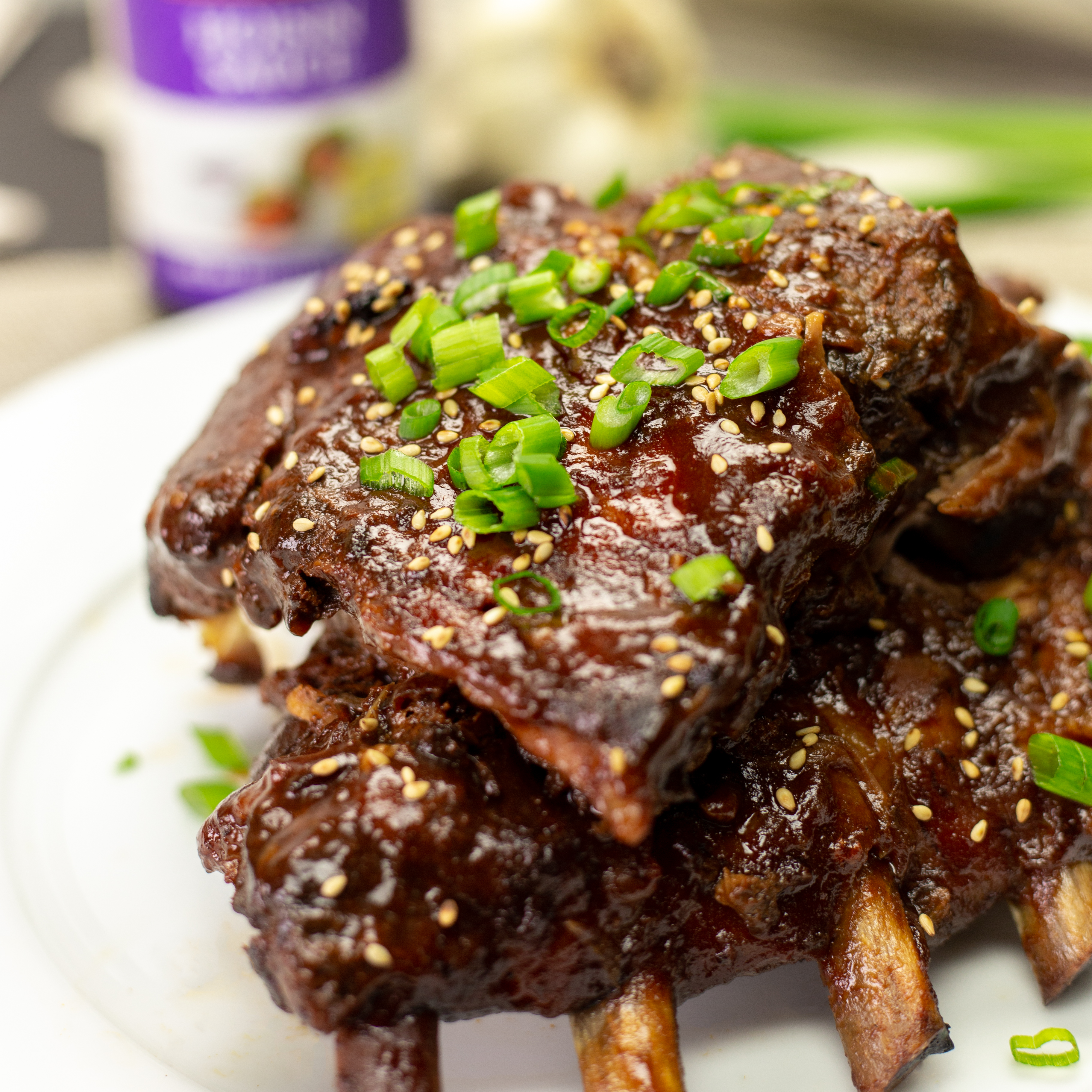 Slow Cooked Hoisin Pork Ribs on a white plate with ingredients in the background