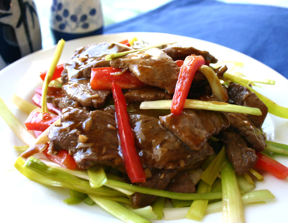 Stir-Fried Beef with Leek dish served on a white plate on a blue tablecloth