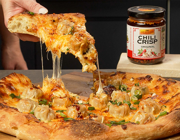 A pizza recipe topped with shu mai, mozzarella cheese, and a spicy chili crisp cream sauce.