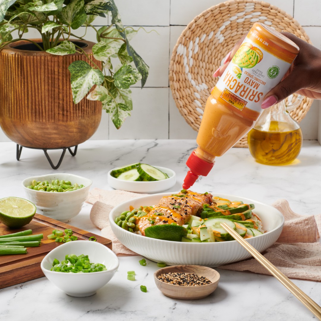 A salmon rice bowl with cucumbers and fresh veggies, drizzled with Lee Kum Kee Sriracha Mayo.