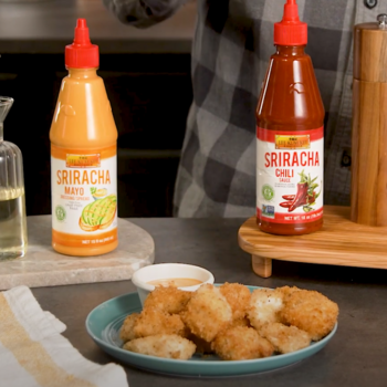 Homemade chicken nuggets recipe on a serving plate, alongside a dipping sauce and the LKK sriracha sauces used in the dish