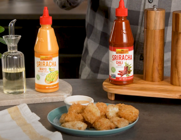 Homemade chicken nuggets recipe on a serving plate, alongside a dipping sauce and the LKK sriracha sauces used in the dish