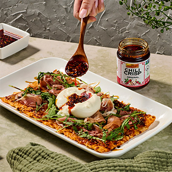 A burrata with prosciutto flatbread recipe topped with original chili crisp.