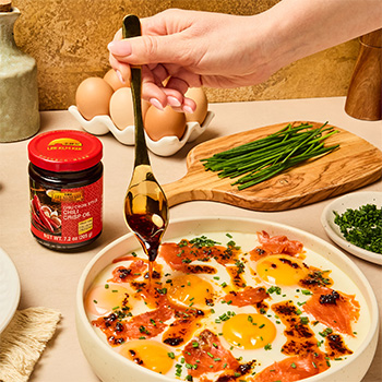 A golden steamed egg recipe topped with smoked salmon, chives, and chili crisp oil.