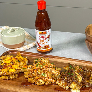 A platter of three loaded fries recipes topped with chili crisp hot honey.