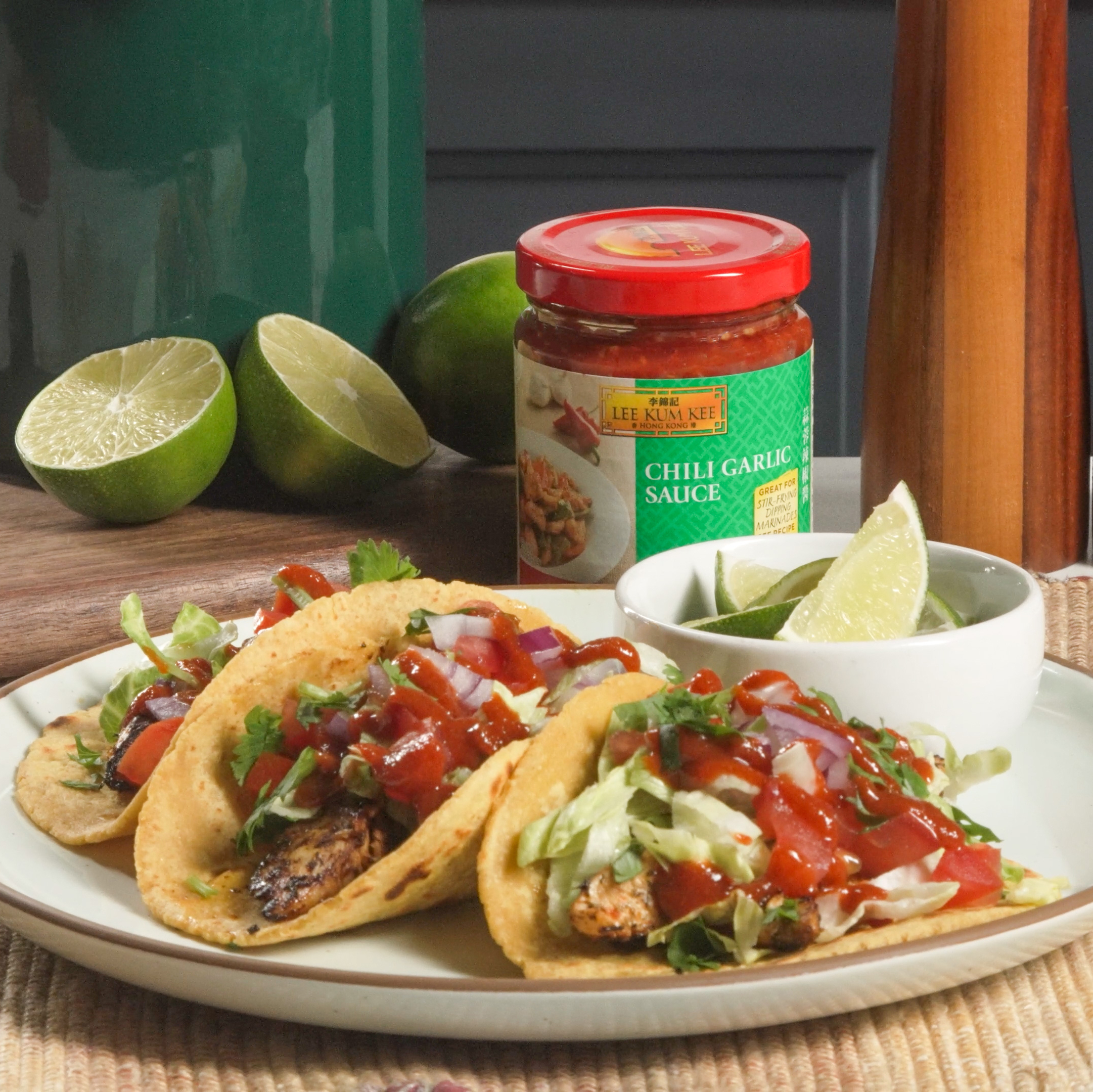 Plate with 3 jerk chicken tacos alongside some recipe ingredients