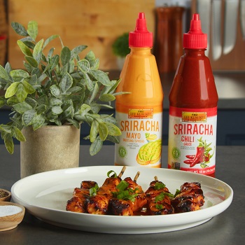 Bang bang chicken skewers on a serving platter, alongside seasonings and Lee Kum Kee sauces used in the recipe