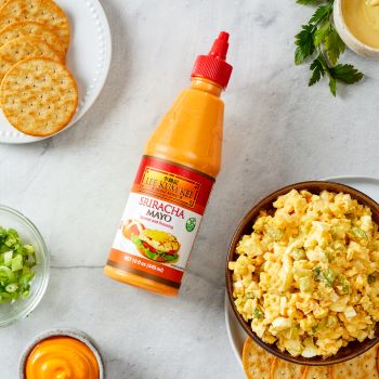 Spicy egg salad recipe in a bowl alongside the Lee Kum Kee sriracha mayo used to make it