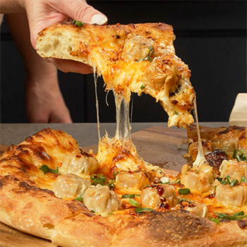 A pizza recipe topped with shu mai, mozzarella cheese, and a spicy chili crisp cream sauce.